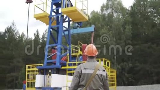 油田技术工人监督原油生产现场的抽油机。 工业油泵千斤顶工作视频