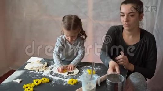 可爱的小白种人女孩3岁和妈妈准备饼干从生面团在家里。视频