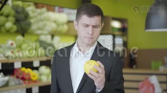 自信认真的男人在超市挑选梨的肖像。 年轻的白人选择黄色水果出售视频
