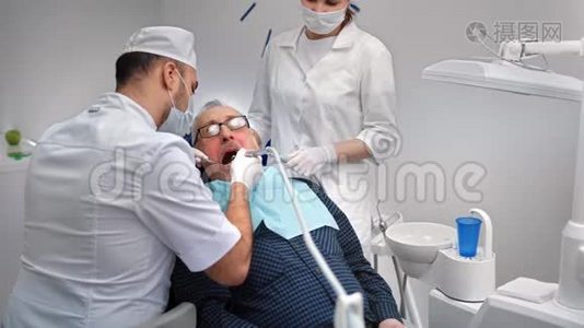 男性口腔医生与老年患者一起使用设备治疗牙齿。 4k龙红相机视频