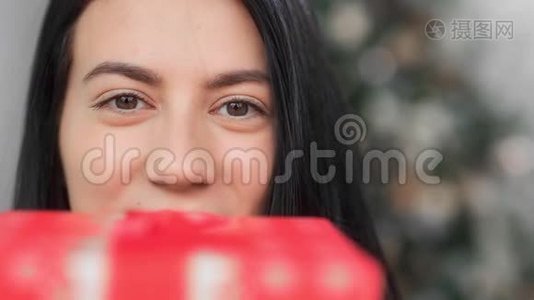 极端近脸滑稽的亚洲女人摆着喜庆的红色礼品盒。 4k龙红相机视频