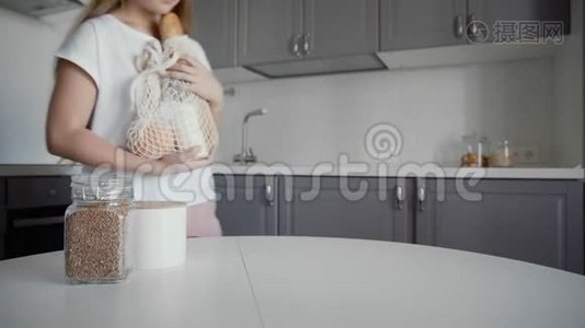 女人在木桌上打开厨房里的面包、牛奶和橘子的购物袋。 零废物之家和生态袋视频
