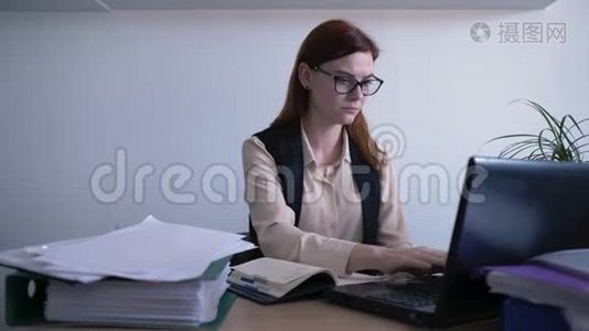忙碌的工作日里，戴着眼镜的漂亮女人看着屏幕，把信息写到笔记本上视频