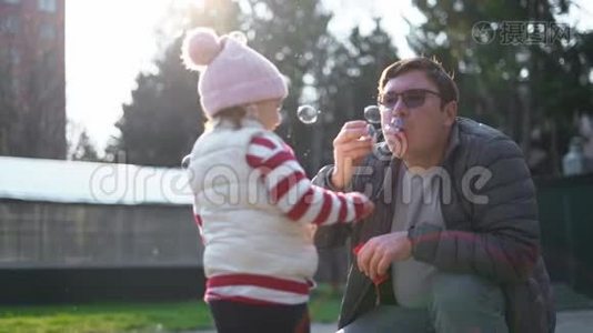 白人男人带着他的孩子在外面吹肥皂泡。 慢动作。 幼儿周末活动，后院视频