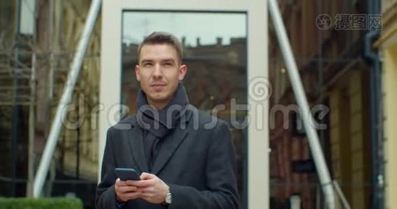 现代办公中心附近使用智能手机的人的肖像。 在社交网络里和他的朋友聊天。 看上去视频