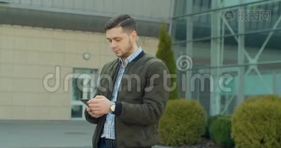 城市街道上的年轻人使用手机，打字，和朋友聊天，男人在户外使用手机。视频