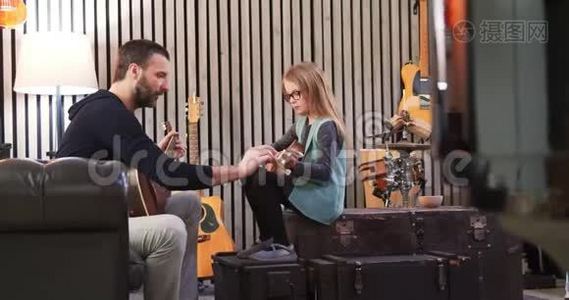 爸爸给女儿教吉他和四弦琴。 小女孩在家学吉他。 侧视。 在家上Ukulele课视频