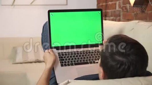 桌上的人正在绿色笔记本电脑屏幕上浏览互联网。 在一个光线充足，舒适的公寓里。 一个人在工作视频