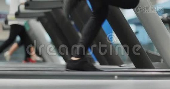 年轻女子在健身房跑步机上跑步。 侧视，腿部细节.. 健身中心女子训练。 妇女行使权力视频
