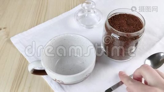 用勺子把玻璃瓶中的冻干咖啡放进杯子里。 喝咖啡因。 特写、木桌、白色餐巾视频