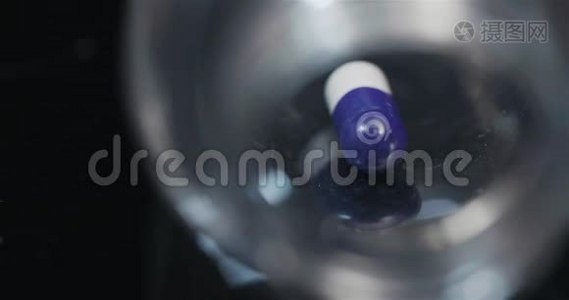 在黑色背景下旋转的小瓶中的单个医疗丸。视频