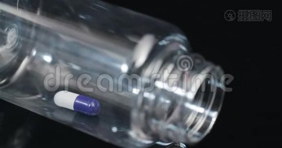 在黑色背景下旋转的小瓶中的单个医疗丸。视频