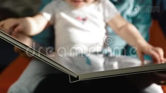 妈妈抱着一个孩子正在玩一本大书，合上视频