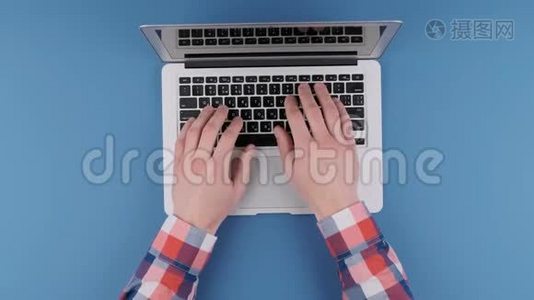 双手在蓝色背景上的笔记本电脑键盘上打字。 上景。视频