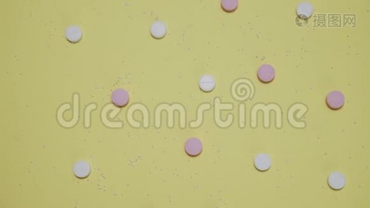 黄色背景的粉色和白色药片视频