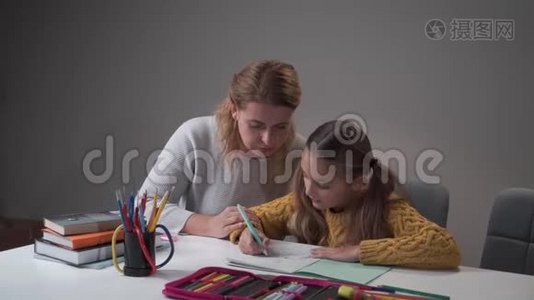 小白种人女孩和妈妈在家做作业。 年轻女子解释女儿的错误。 父母视频