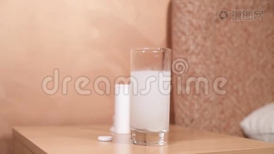 床头柜上有一个玻璃杯，里面溶解了一片阿司匹林。视频