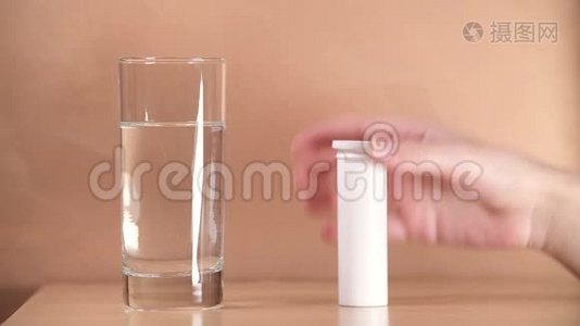 在床头柜上特写一个玻璃杯，其中一个女孩扔了一颗药丸视频