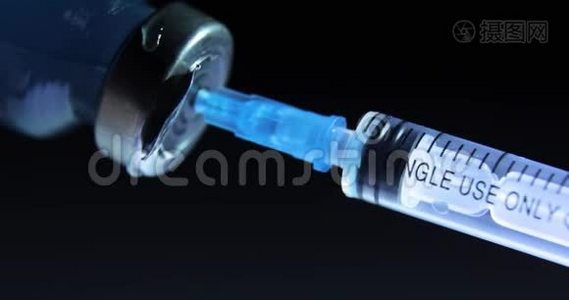 在黑色背景下将蓝色冠状病毒疫苗注射到注射器中，COVID-19。视频