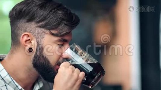 年轻的嬉皮士用玻璃杯喝着新鲜的工艺啤酒，闭着眼睛品尝着味道视频