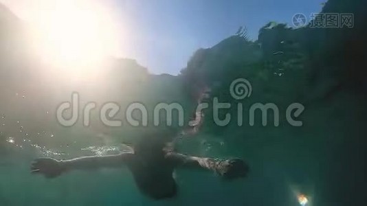 慢镜头：人跳进海里，阳光照亮他视频