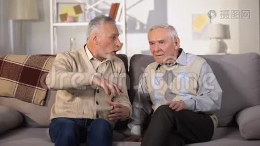 老人向失聪的朋友解释什么，坐在家里的沙发上，有问题视频
