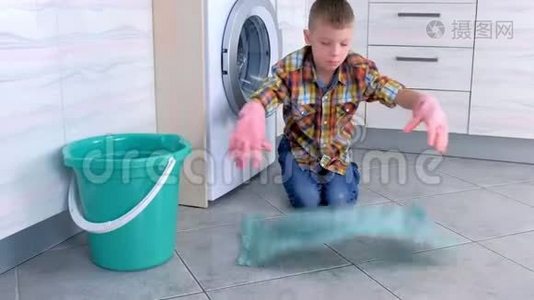 穿橡胶手套的男孩在厨房里洗地板。 儿童`的家庭责任。视频