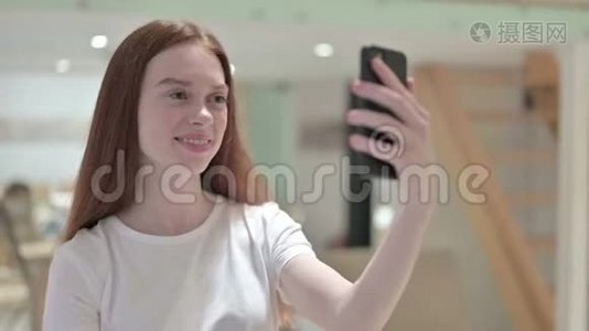 红头发青年妇女在智能手机上视频聊天的画像视频