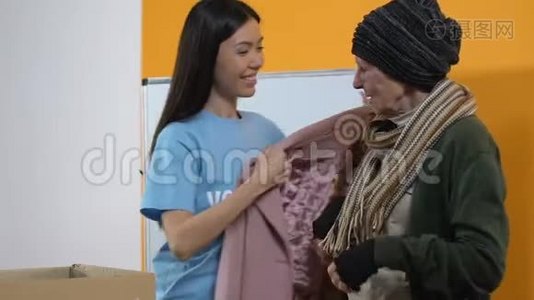年轻的女志愿者为贫穷的无家可归的微笑妇女送冬衣视频