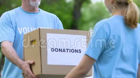 老年男性志愿者为年轻女性提供捐款箱、慈善和支持视频
