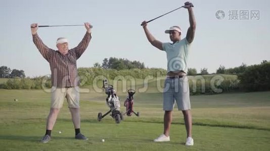成熟的白种人和年轻的中东人在高尔夫球场打高尔夫球。 玩家在游戏前热身视频