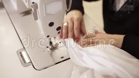 高角度视角的女性手与彩色美甲的过程中，创造婚纱白色礼服。 服装设计师视频