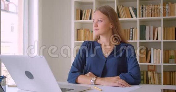 年轻漂亮的白种人女商人的特写镜头，她正开心地坐在办公桌前看着镜头视频