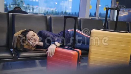 美丽迷人的女人睡在机场航站楼。 长途连接飞行时差。 女人睡在视频