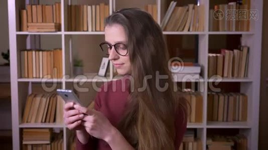 戴着眼镜的年轻白种人女学生的特写镜头，她用手机笑着开心地看着镜头视频