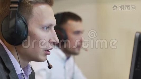 男性呼叫中心代理在无线耳机咨询在线客户端.. 利用电脑，商人们在谈话视频