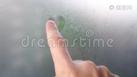 一根手指在雾蒙蒙的窗户上画着微笑。视频