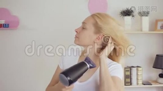 一个四十多岁的女人用吹风机擦干她染好的金发。视频