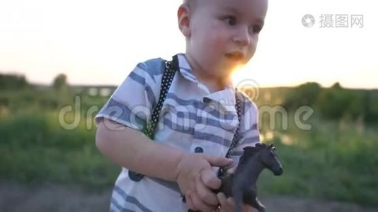 可爱的男孩拿着一个小马玩具，在日落时快乐地在路上奔跑视频