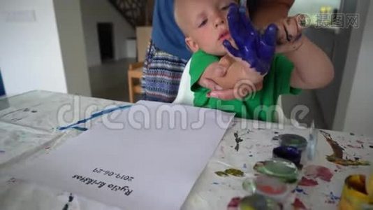 母亲和幼儿儿子用水彩在纸上制作手印邮票视频