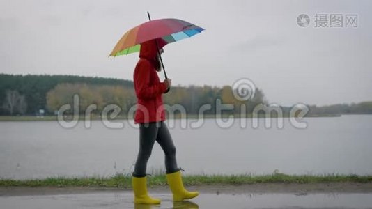 穿着黄色靴子的女人和一支雨伞穿过秋天的水坑视频