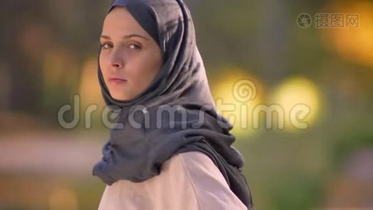 特写照片上的穆斯林女孩在头巾，转动相机和认真观看。视频