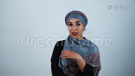 年轻美丽的阿拉伯女人微笑着调整她的头巾，她的手在孤立的白色背景上移动视频