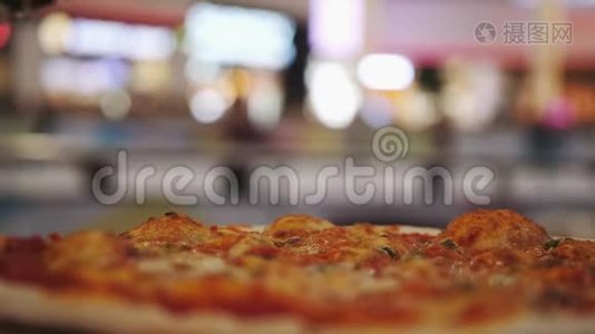 在披萨上倒入油的特写镜头，背景上有模糊的灯光。 慢动作视频