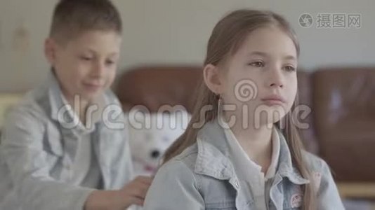 双胞胎兄弟淘气的男孩在舒适的客厅里玩着拉扯他可爱妹妹的头发和微笑视频