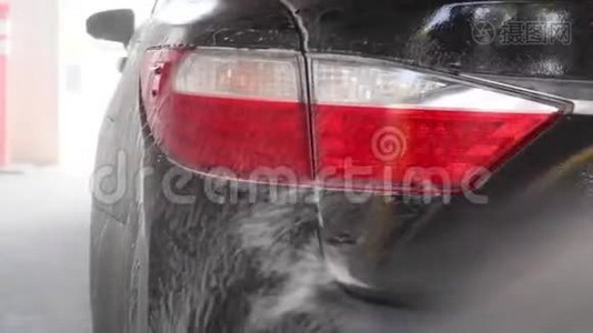 专业工人正在洗车时用压力垫圈清洗一辆黑色汽车。视频