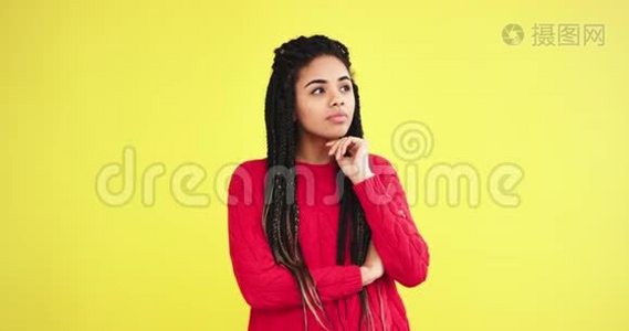 一位非洲魅力四射的女士非常好奇地想着一个黄色背景的工作室里的东西，她穿过了视频