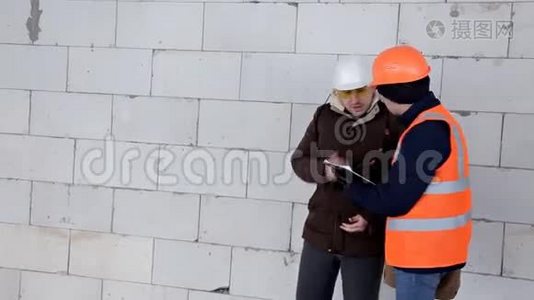 顾客戴着防护头盔，核实建筑工人对正在施工的物体的工作，人们走过视频