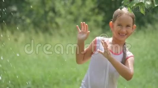 美丽的女孩在花园里泼水的肖像。 女孩完全湿透了，这`是非常炎热和快乐的一天。 概念视频