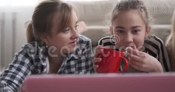 女孩一边看着笔记本电脑上的媒体内容一边喝咖啡和爆米花视频